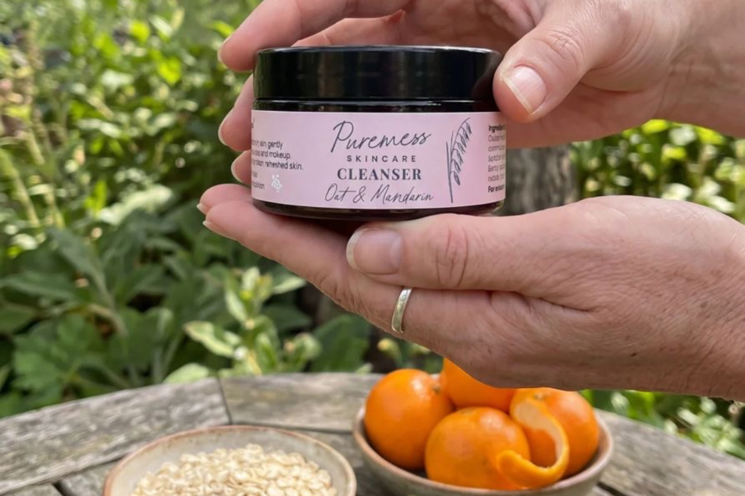 oat & mandarin cleanser being held above a table with a bowl of oats and a bowl of mandarins