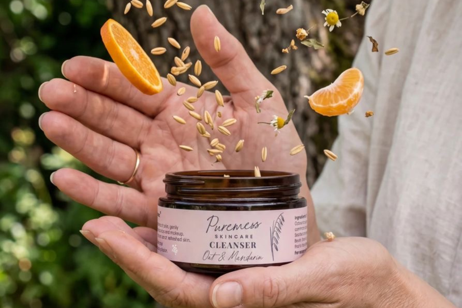 oat and mandarin cleanser with lid off and ingredients bursting out