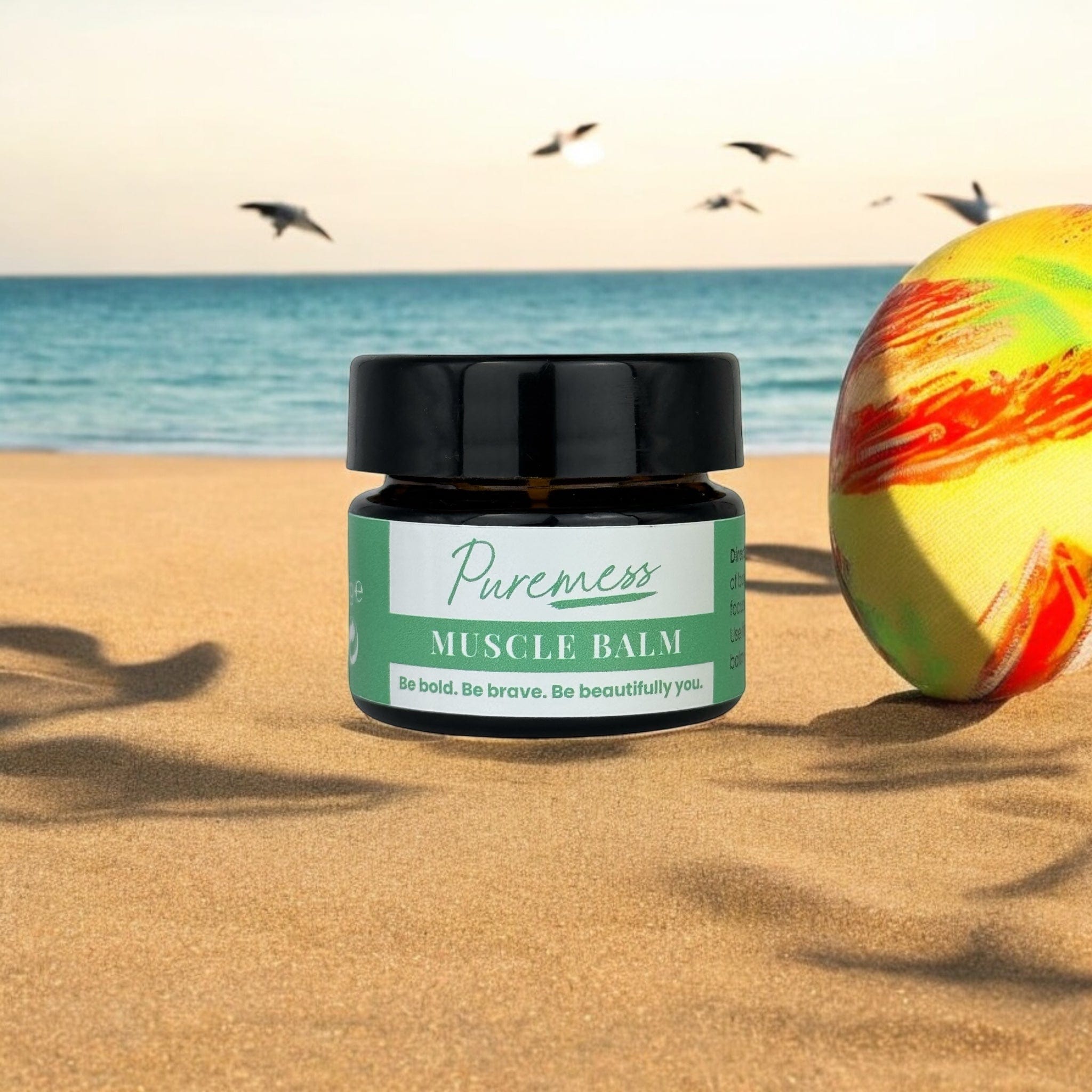Muscle Balm in eco-friendly Puremess packaging on sandy beach with seashells, highlighting natural skincare and botanical. - Muscle Balm - PUREMESS SKINCARE