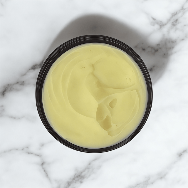 Open container of pale yellow Rejuvenating Face Cream with smooth texture on white marble surface, showcasing natural. - Rejuvenating Face Cream - PUREMESS SKINCARE