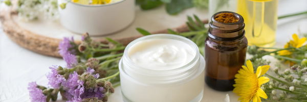 pot of white cream and an amber bottle surrounded by flowers