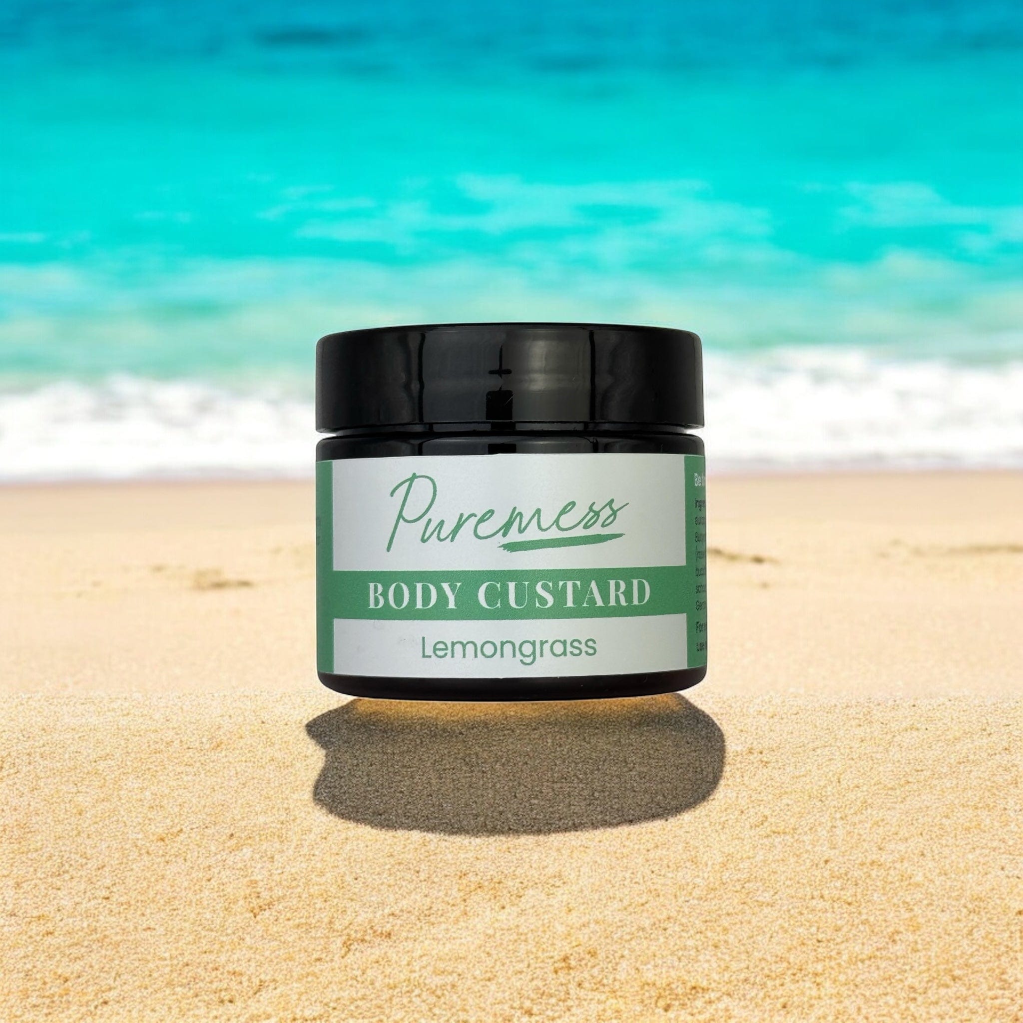 Lemongrass body custard with black lid on sandy beach, natural skincare with botanical ingredients, sustainable packaging,. - Lemongrass Body Custard - PUREMESS SKINCARE