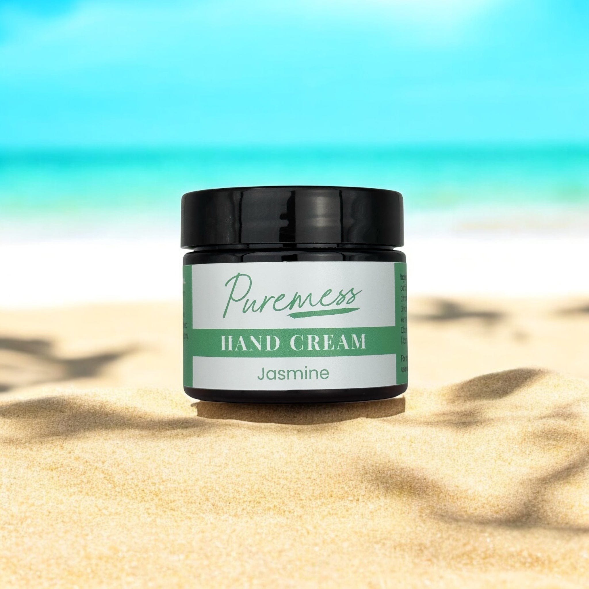 Jasmine hand cream in eco-friendly black container with Puremess label on sandy beach, natural skincare, botanical. - Jasmine Hand Cream - PUREMESS SKINCARE