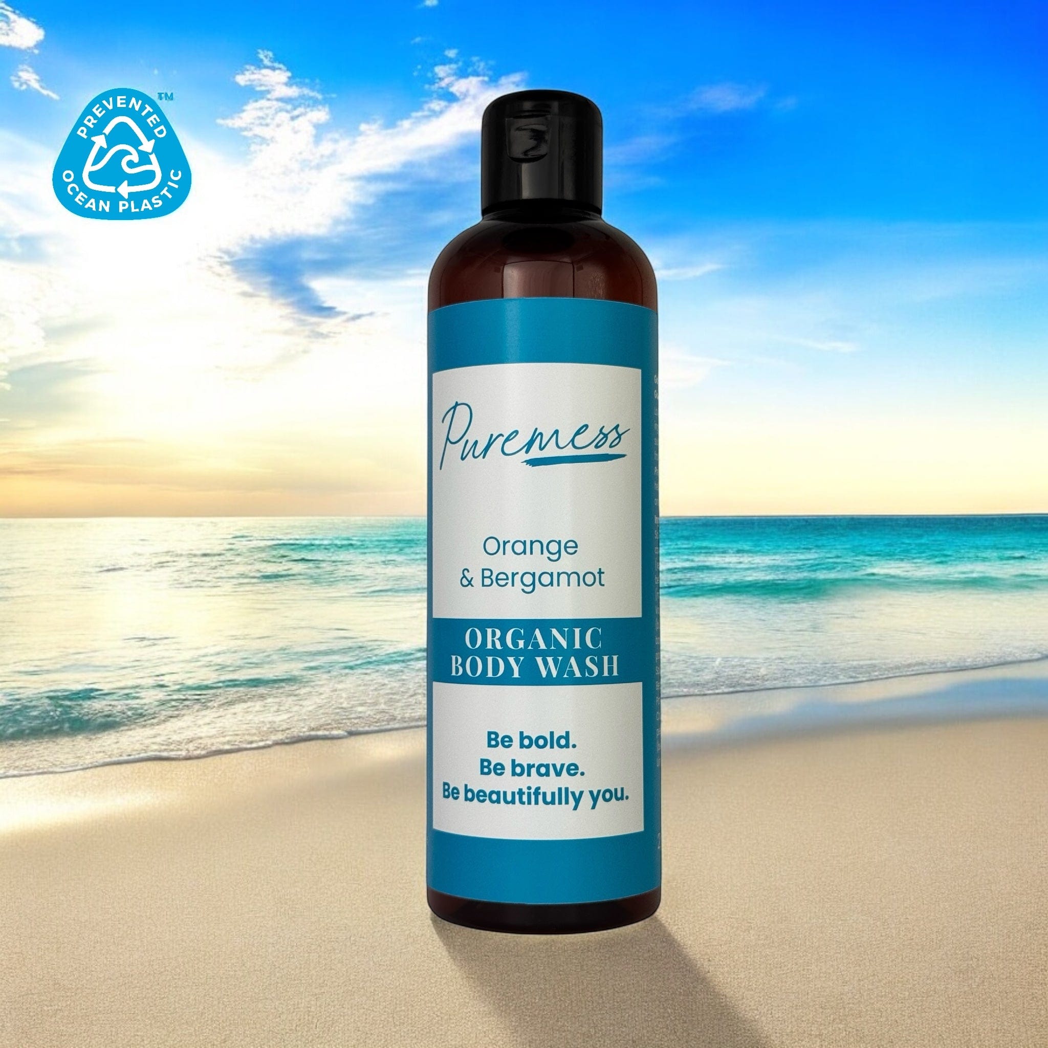 Puremess Orange & Bergamot organic body wash with sustainable packaging against a beach backdrop, natural skincare,. - Orange & Bergamot Organic Body Wash - PUREMESS SKINCARE
